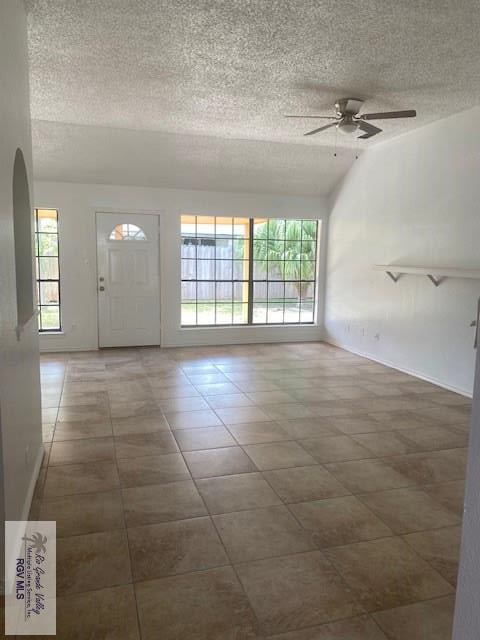 tiled foyer with a textured ceiling, vaulted ceiling, ceiling fan, and a healthy amount of sunlight