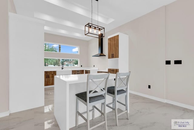 3330 Calle Bolivia, Brownsville, TX 78521 - kitchen with light marble finish flooring, brown cabinets, wall chimney exhaust hood, light countertops, and pendant lighting