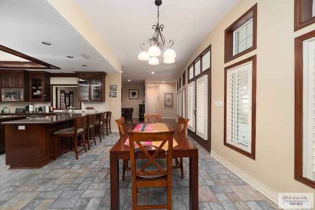 5363 Rustic Manor Dr, Brownsville, TX 78526 - dining room featuring stone tile floors, a chandelier, recessed lighting, baseboards, and bar