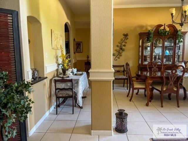 dining room with ornate columns, light tile patterned floors, ornamental molding, and a notable chandelier