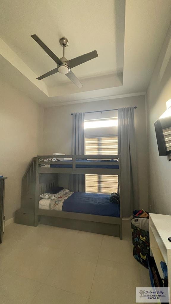 tiled bedroom featuring a tray ceiling and ceiling fan