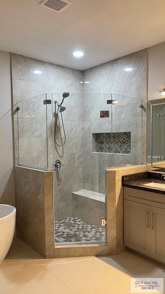 bathroom with tile patterned flooring, vanity, visible vents, a freestanding bath, and a shower stall