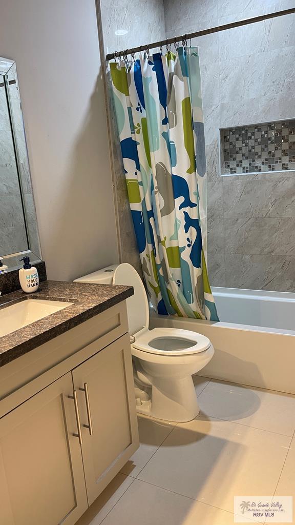 bathroom featuring toilet, tile patterned flooring, shower / bathtub combination with curtain, and vanity