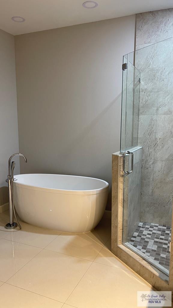 bathroom featuring a stall shower, a soaking tub, and tile patterned flooring