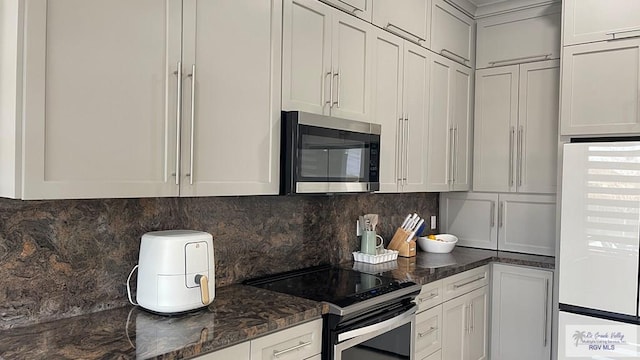 kitchen with tasteful backsplash, dark stone counters, and stainless steel appliances