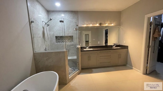 bathroom featuring double vanity, a freestanding tub, a shower stall, and a sink