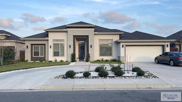 prairie-style house with a garage, concrete driveway, a shingled roof, and stucco siding