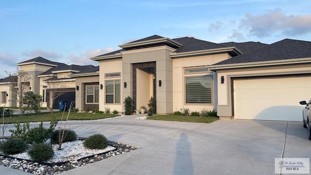 prairie-style home featuring a garage, driveway, a shingled roof, and stucco siding