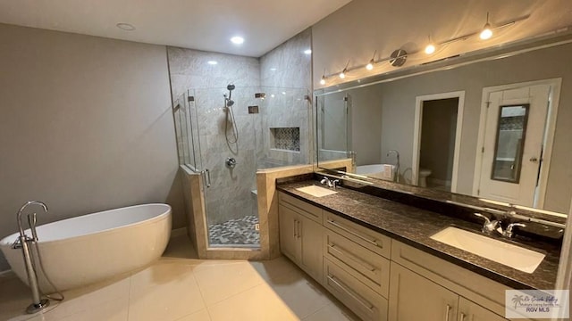 bathroom featuring double vanity, a freestanding bath, a sink, a shower stall, and tile patterned floors