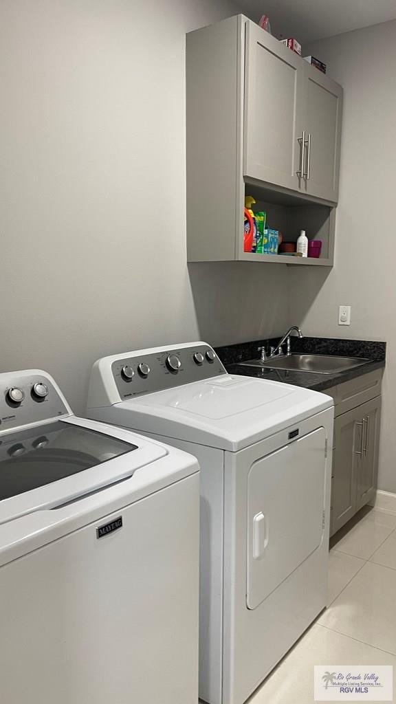 washroom with cabinet space, washer and dryer, a sink, and light tile patterned flooring