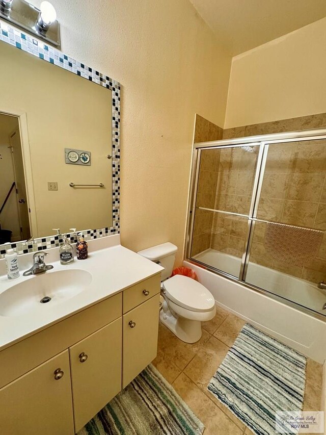 full bathroom featuring toilet, vanity, tile patterned floors, and shower / bath combination with glass door