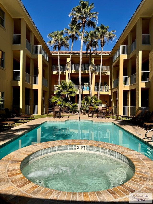 view of swimming pool featuring a hot tub