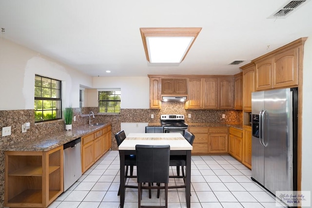 kitchen featuring sink, kitchen peninsula, a breakfast bar, light tile patterned floors, and appliances with stainless steel finishes