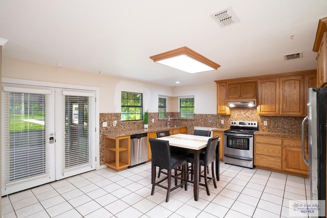 kitchen featuring light stone countertops, appliances with stainless steel finishes, decorative backsplash, and light tile patterned flooring