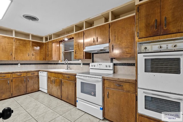 kitchen with light tile patterned flooring, white appliances, tasteful backsplash, and sink