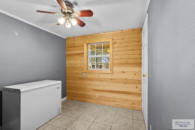 laundry area with wooden walls, crown molding, light tile patterned floors, and ceiling fan