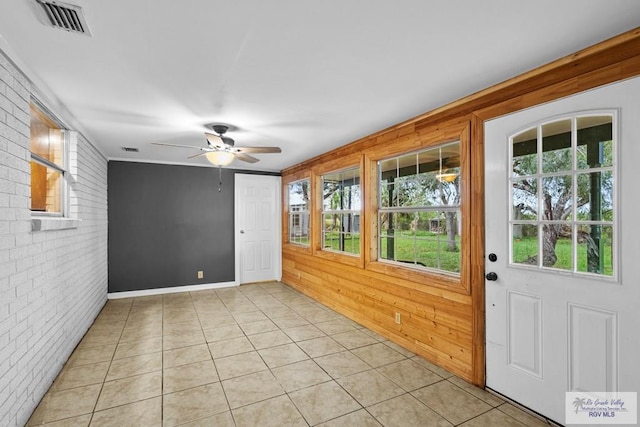 interior space with wooden walls, light tile patterned floors, and brick wall