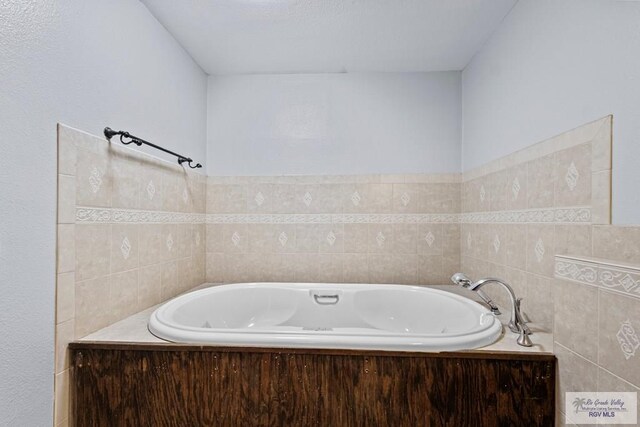 bathroom featuring a washtub and tile walls