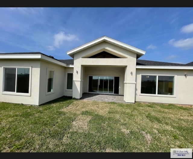 back of house with a lawn and stucco siding