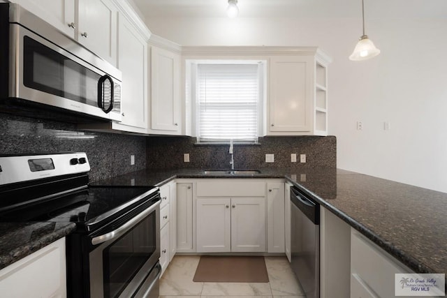 110 E Retama St, South Padre Island, TX 78597 - kitchen featuring appliances with stainless steel finishes, backsplash, white cabinetry, dark stone countertops, and light marble finish floors
