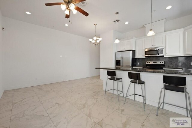 110 E Retama St, South Padre Island, TX 78597 - kitchen with appliances with stainless steel finishes, a ceiling fan, a kitchen bar, white cabinetry, and recessed lighting