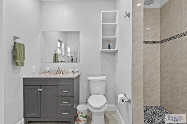 full bath featuring baseboards, tiled shower, vanity, and toilet