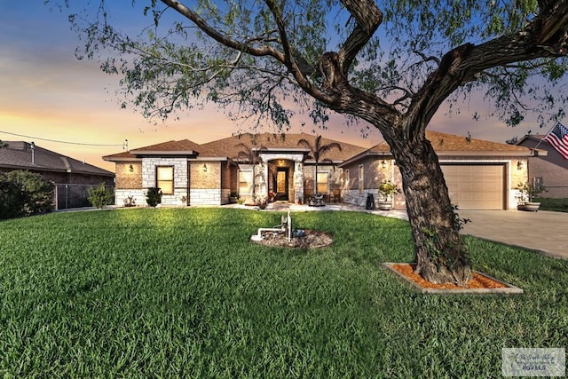 view of front of home featuring an attached garage, fence, stone siding, a yard, and concrete driveway