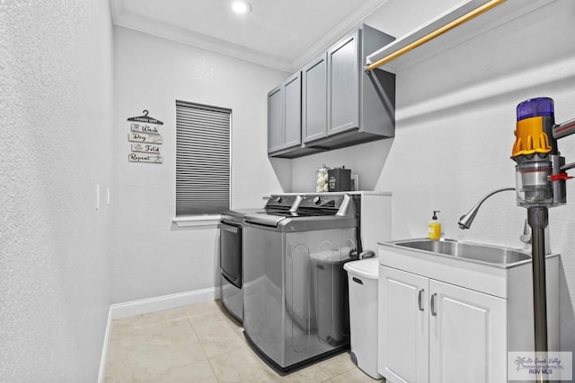 clothes washing area featuring cabinet space, baseboards, independent washer and dryer, crown molding, and a sink