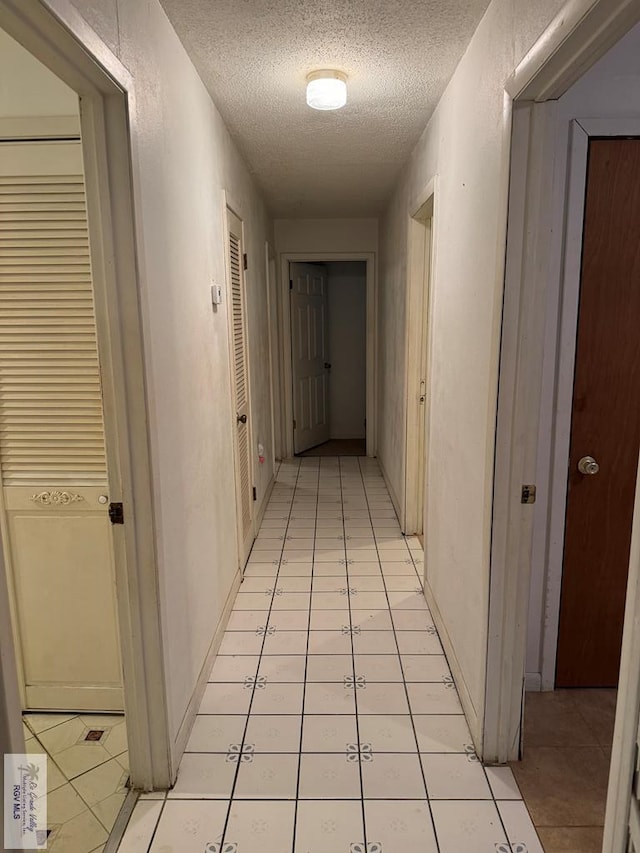 corridor featuring light tile patterned floors and a textured ceiling