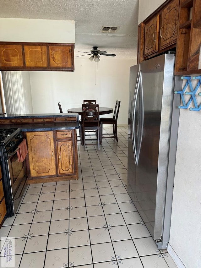 kitchen with black range with gas stovetop, stainless steel refrigerator with ice dispenser, ceiling fan, and light tile patterned flooring