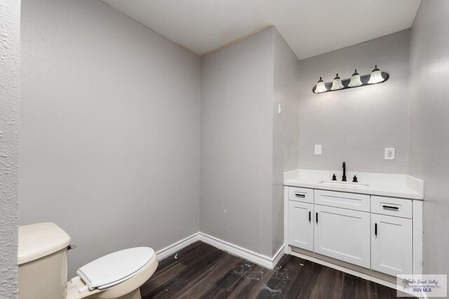 136 Garden St, Brownsville, TX 78520 - bathroom with toilet, wood finished floors, baseboards, and vanity