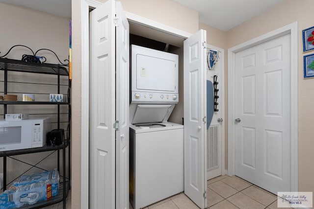 washroom with stacked washing maching and dryer and light tile patterned floors