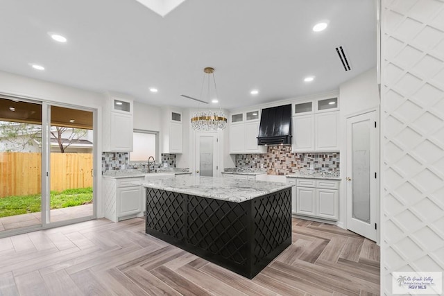 kitchen featuring pendant lighting, light parquet floors, white cabinetry, a center island, and custom range hood