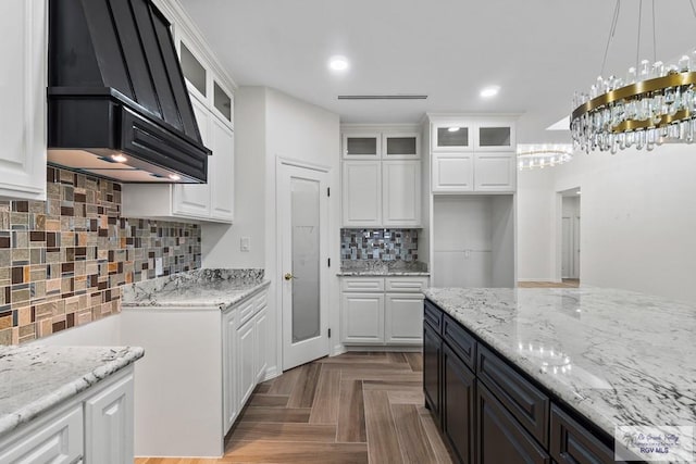 kitchen featuring white cabinetry, tasteful backsplash, decorative light fixtures, parquet floors, and light stone countertops