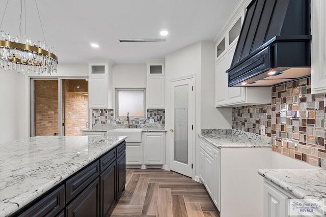 kitchen with hanging light fixtures, sink, white cabinets, and dark parquet floors