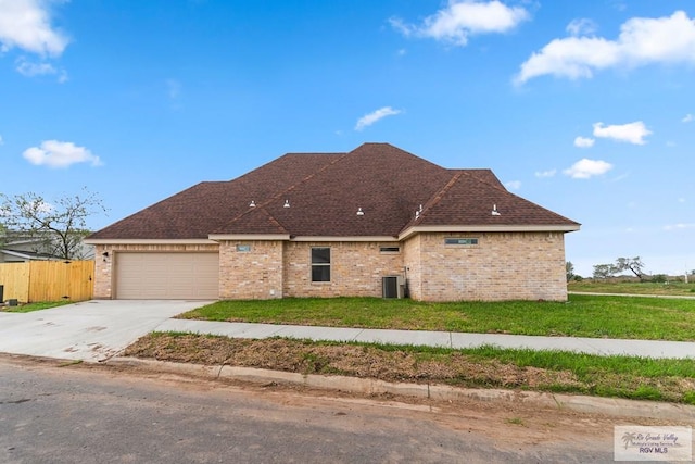 view of front facade with cooling unit, a garage, and a front lawn