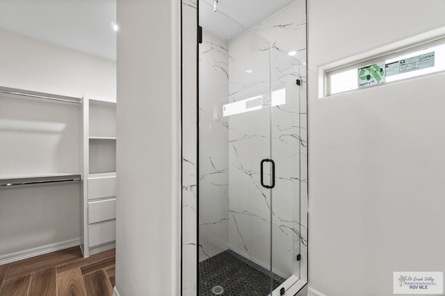 bathroom with a shower with door and wood-type flooring