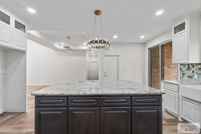 kitchen with white cabinetry, hanging light fixtures, a center island, and light parquet flooring