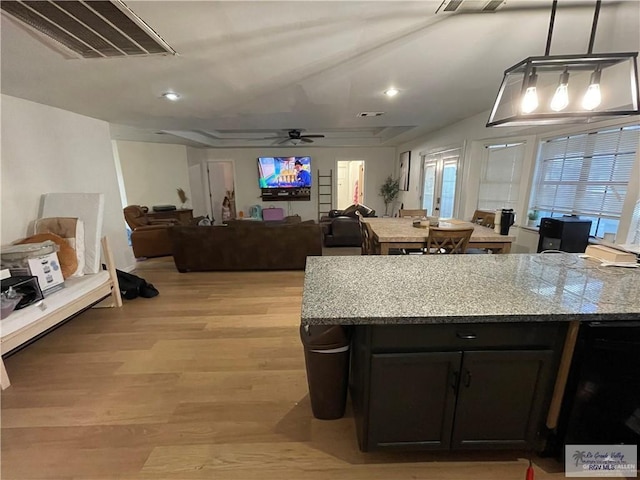 kitchen featuring light stone countertops, pendant lighting, light hardwood / wood-style floors, and ceiling fan