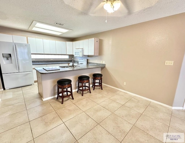 114 Willow Cir, Harlingen, TX 78552 - kitchen with white appliances, a sink, a peninsula, light tile patterned floors, and a textured ceiling