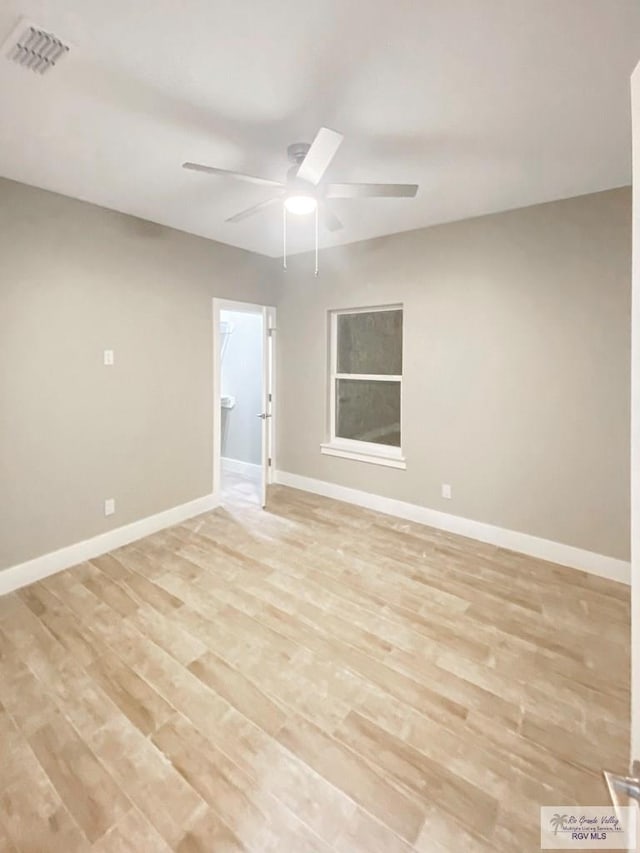 empty room with light wood finished floors, baseboards, a ceiling fan, and visible vents