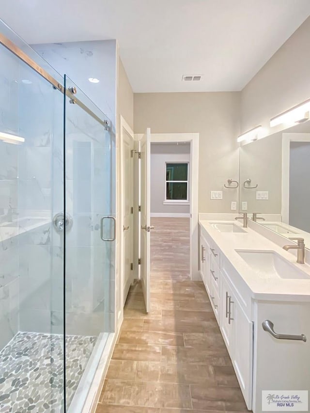 full bathroom with a stall shower, wood finished floors, a sink, and visible vents