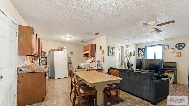 dining area featuring a textured ceiling, ceiling fan, and sink