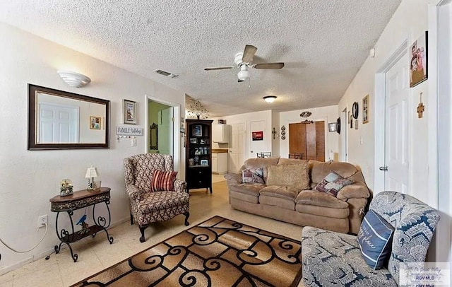 living room featuring ceiling fan and a textured ceiling