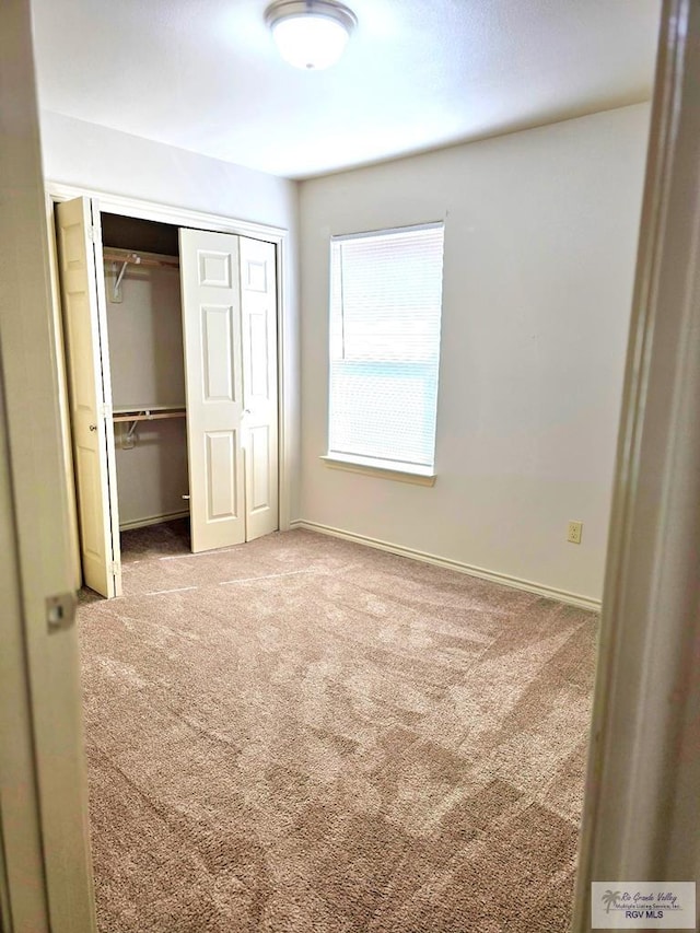 unfurnished bedroom with a closet, carpet, and baseboards