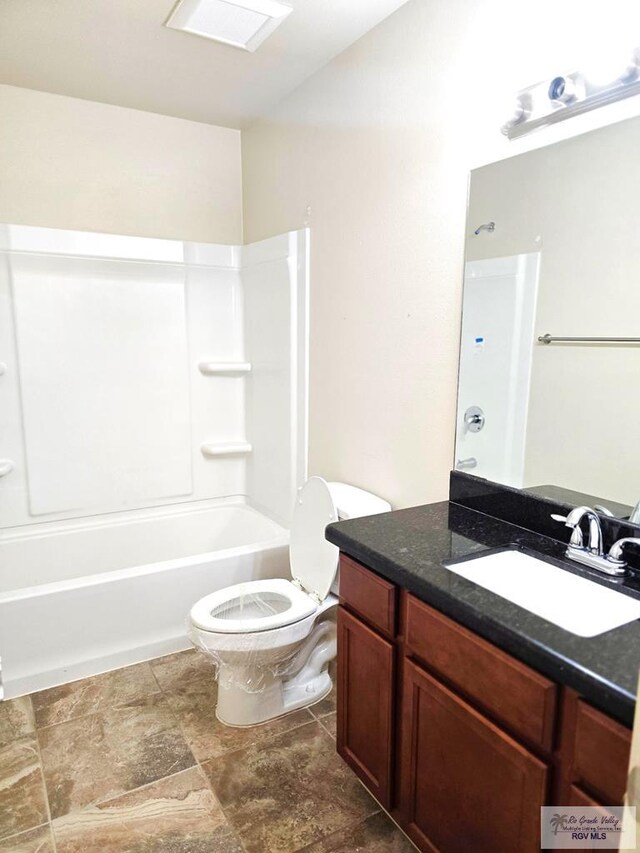 bathroom with vanity, lofted ceiling, toilet, washtub / shower combination, and stone finish flooring