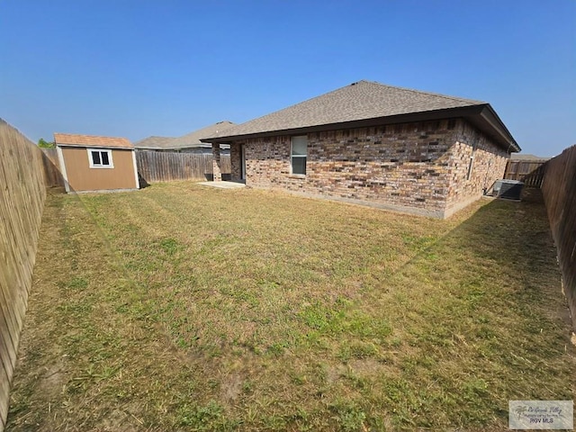 exterior space featuring a storage unit, brick siding, a fenced backyard, an outbuilding, and a lawn