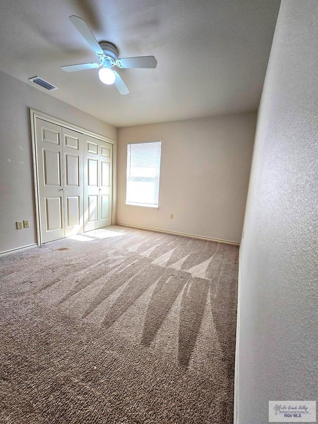 unfurnished bedroom with carpet flooring, a ceiling fan, baseboards, visible vents, and a closet