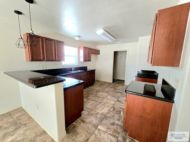 kitchen featuring a sink, dark countertops, hanging light fixtures, and a peninsula