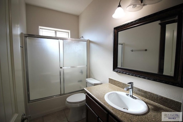 full bathroom with tile patterned floors, vanity, toilet, and bath / shower combo with glass door